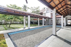Un espace extérieur abrité, doté d’une piscine, et entouré d’un jardin où l’herbe et les arbres sont soigneusement entretenus.