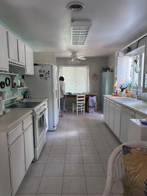 A kitchen with white cabinets, a stove, and a window with blinds. - Enjoyable 2-bedroom house in Hilton Head Island (Hilton Head Island)