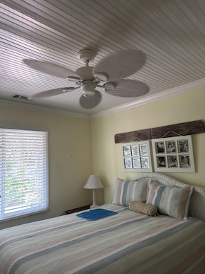 A bedroom with a bed, a ceiling fan, a window with blinds, and wall-mounted pictures. - Enjoyable 2-bedroom house in Hilton Head Island (Hilton Head Island)