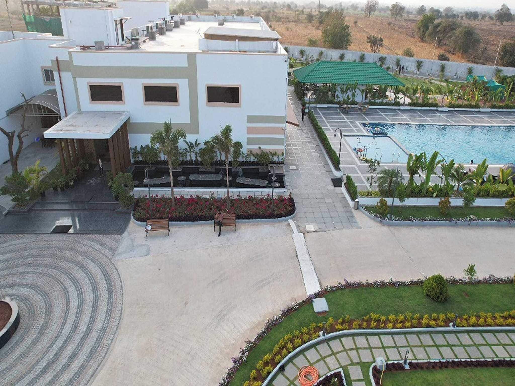A hotel with a swimming pool, a covered outdoor area, and a landscaped garden.