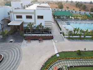 A hotel with a swimming pool, a covered outdoor area, and a landscaped garden.