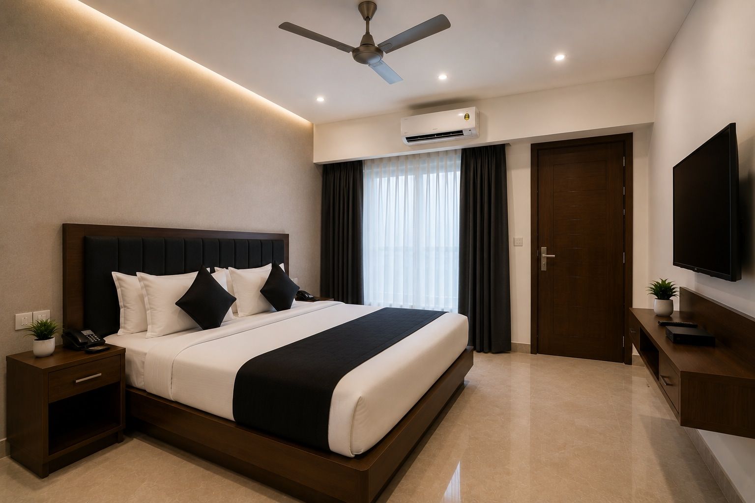 A modern hotel room with a large bed, a ceiling fan, an air conditioning unit, a TV, and a small bedside table with a plant.