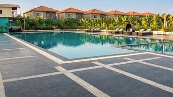 A swimming pool with lounge chairs and a tiled deck area.
