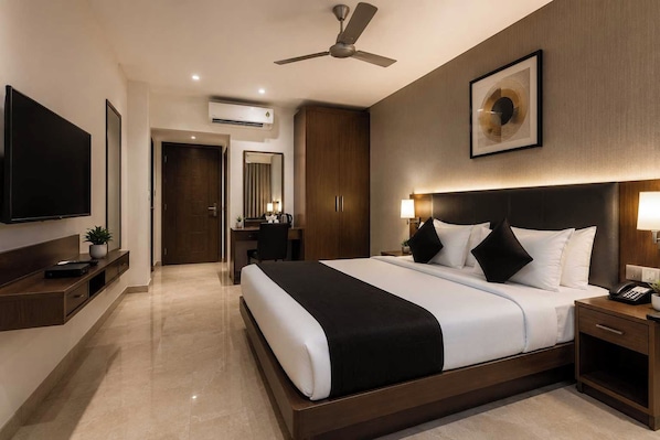 Une chambre d’hôtel avec un lit, une table de chevet, une lampe et un ventilateur de plafond.