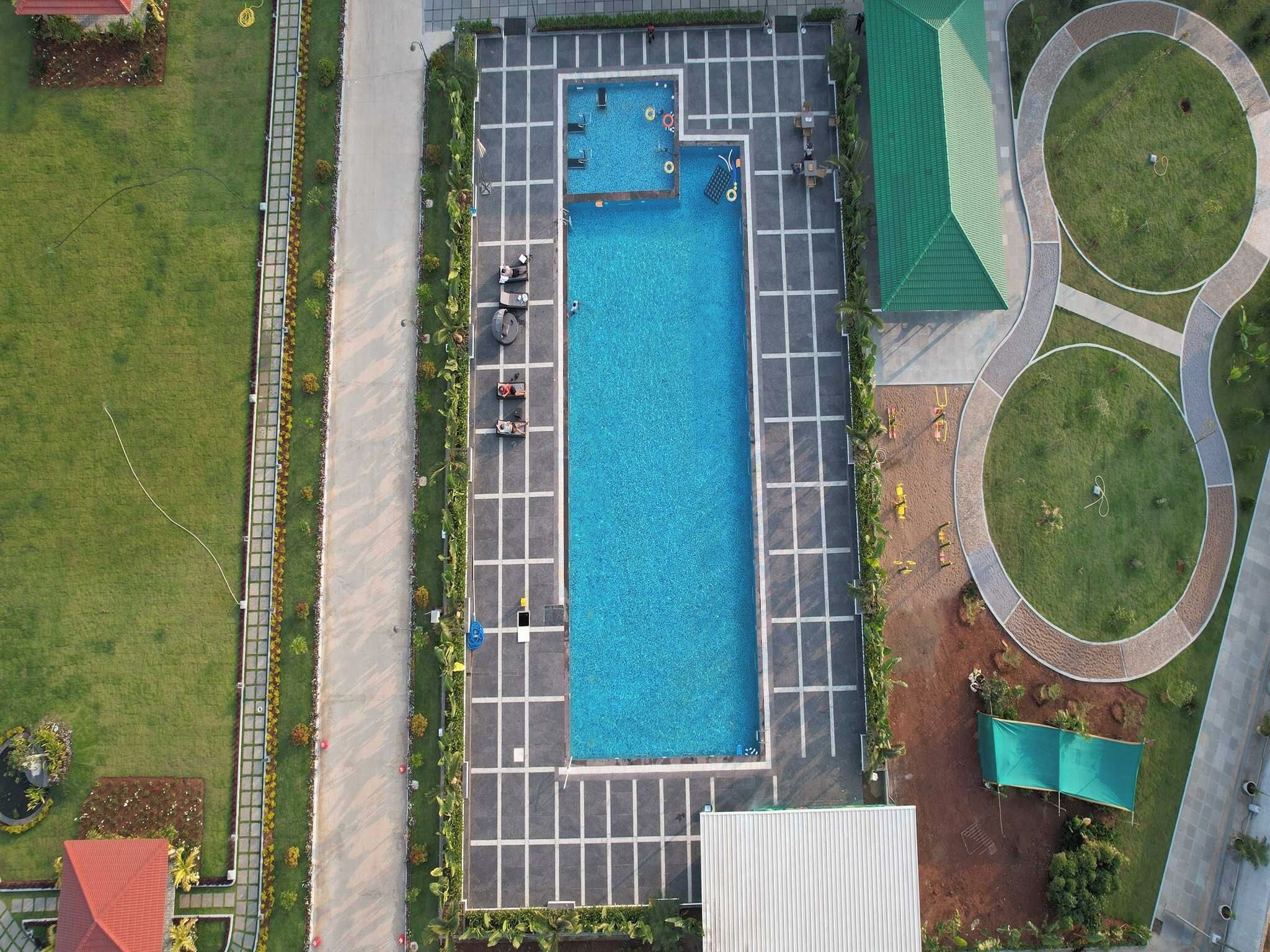 An aerial view of a swimming pool with surrounding pathways and greenery.
