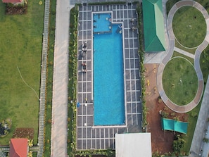An aerial view of a swimming pool with surrounding pathways and greenery.