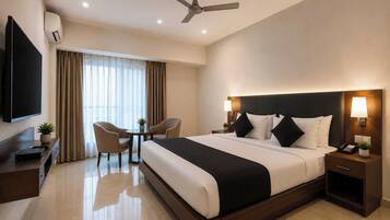 Ein Hotelzimmer mit einem großen Bett, einem Schreibtisch, einem Stuhl, einem Fernseher und einem Deckenventilator.