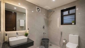 A modern bathroom with a large mirror, a sink, a toilet, a shower, and a small window. - Palette Haritha Wellness Resort CheckIn (Sangareddy)