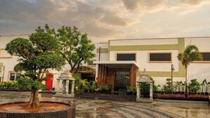 A courtyard with a fountain, trees, and a building with large windows. - Palette Haritha Wellness Resort CheckIn (Sangareddy)