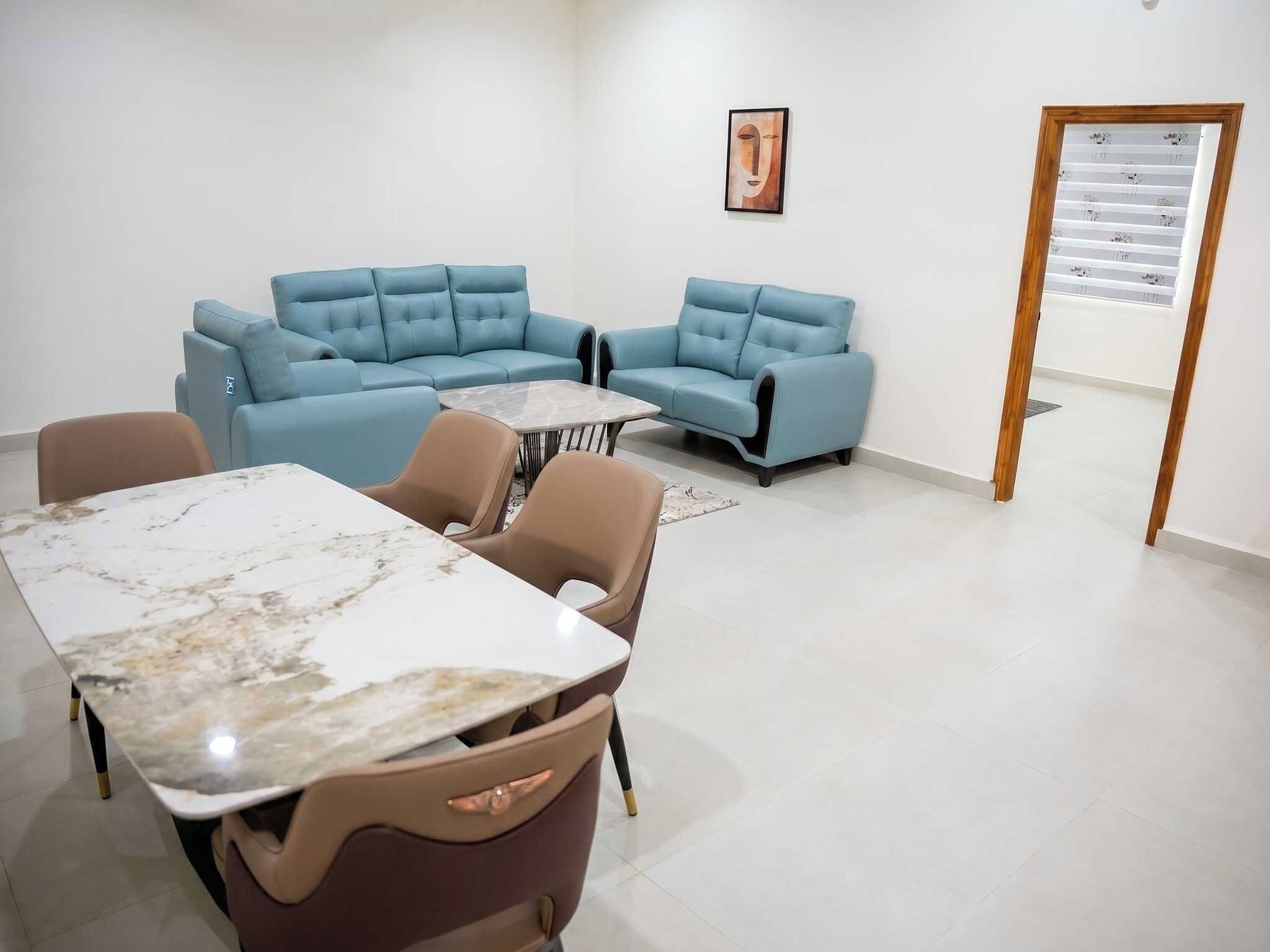 Um interior moderno com um sofá seccional, uma mesa de mármore e uma parede estampada.