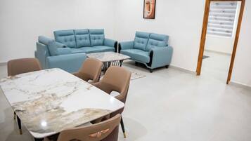 Um interior moderno com um sofá seccional, uma mesa de mármore e uma parede estampada.