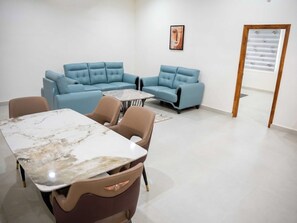 A modern interior with a sectional sofa, a marble table, and a patterned wall. - Palette Haritha Wellness Resort CheckIn (Momanpet)