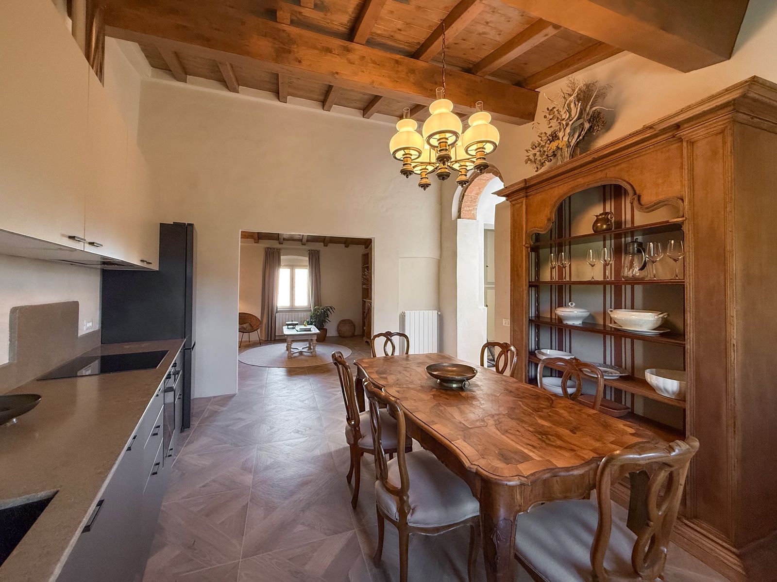 A kitchen with a wooden table, chairs, and a chandelier.