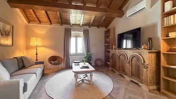 Een woonkamer met een bank, een salontafel, een televisie en een boekenkast.