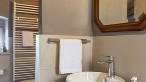 Een badkamer met een witte wastafel, een spiegel en een handdoekhouder.