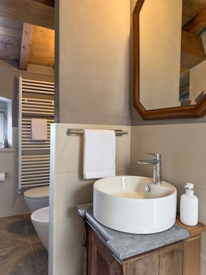 A bathroom with a white sink, a mirror, and a towel rack. - Vrbo Property (Riparbella)