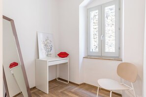A room with a white desk, a chair, a large mirror, and a window with a view of stone walls. - Nice apartment for 4 guests with A/C, WIFI, close to Assisi (Bevagna)
