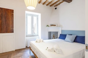 Ein Schlafzimmer mit Bett, Fenster, Kamin und Holzboden.