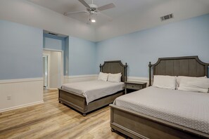 Ein Schlafzimmer mit zwei Betten, einem Deckenventilator und einer Tür zu einem anderen Raum.