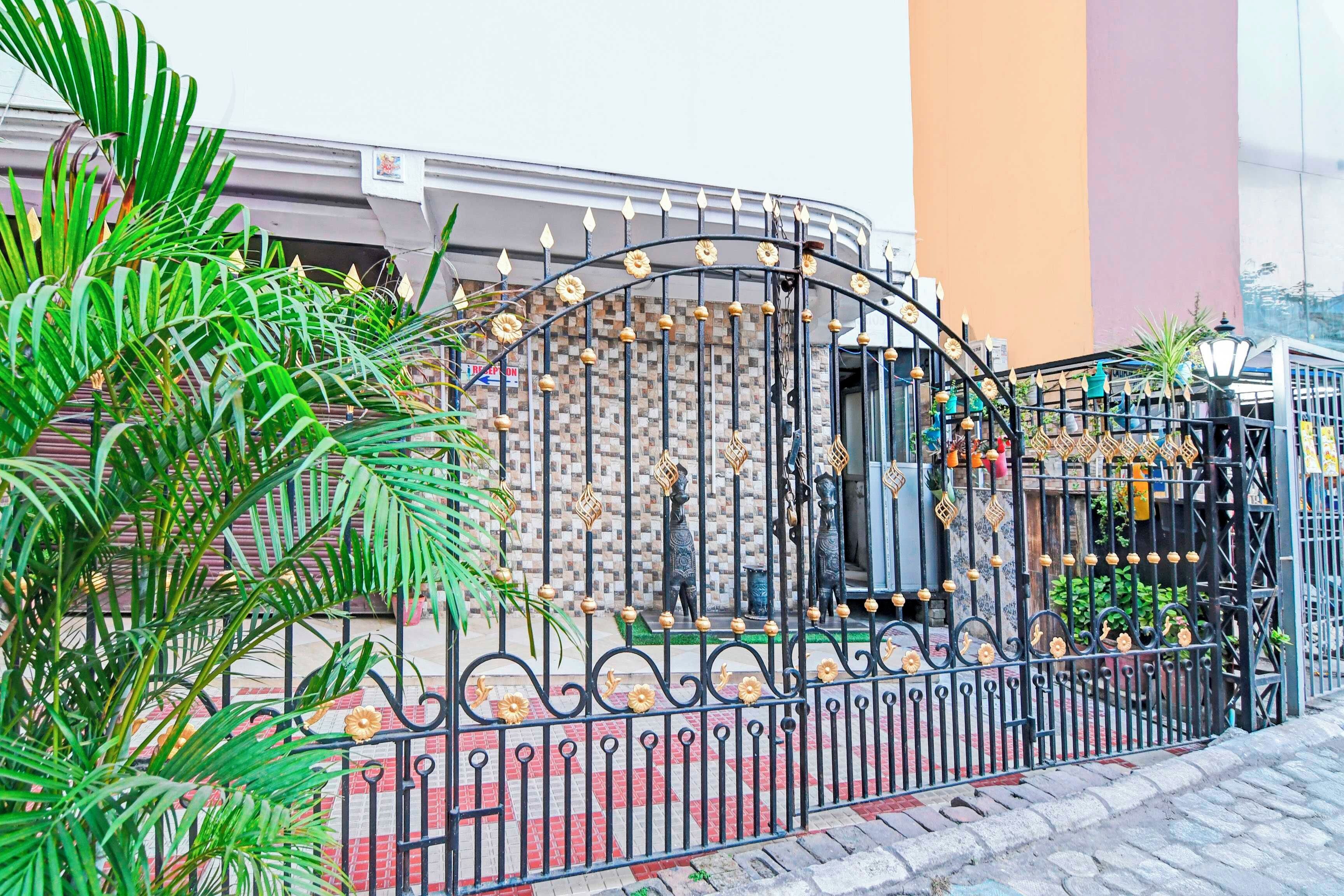 Una entrada protegida por una reja con detalles de metal, un muro de azulejos y plantas en macetas.