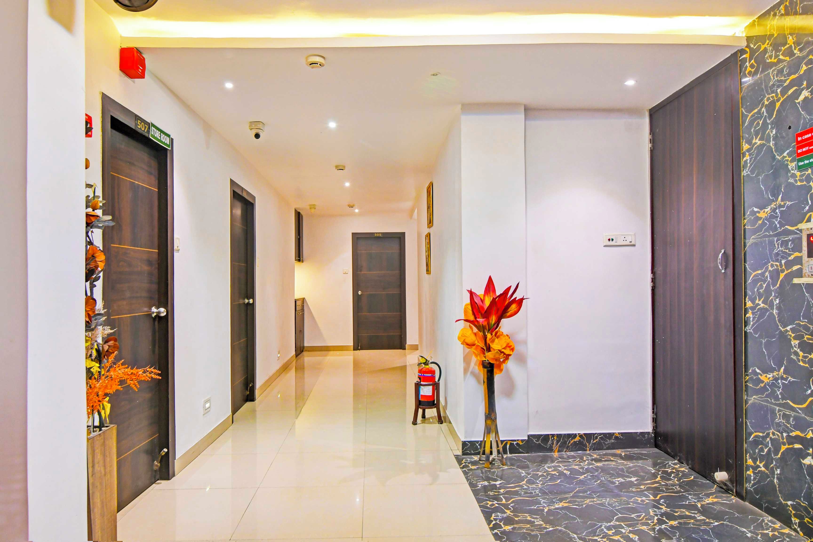 A hotel hallway with a marble floor, a fire extinguisher, and a decorative plant.