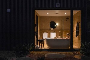 A modern bathroom with a freestanding bathtub, a towel rack, and a shower area.