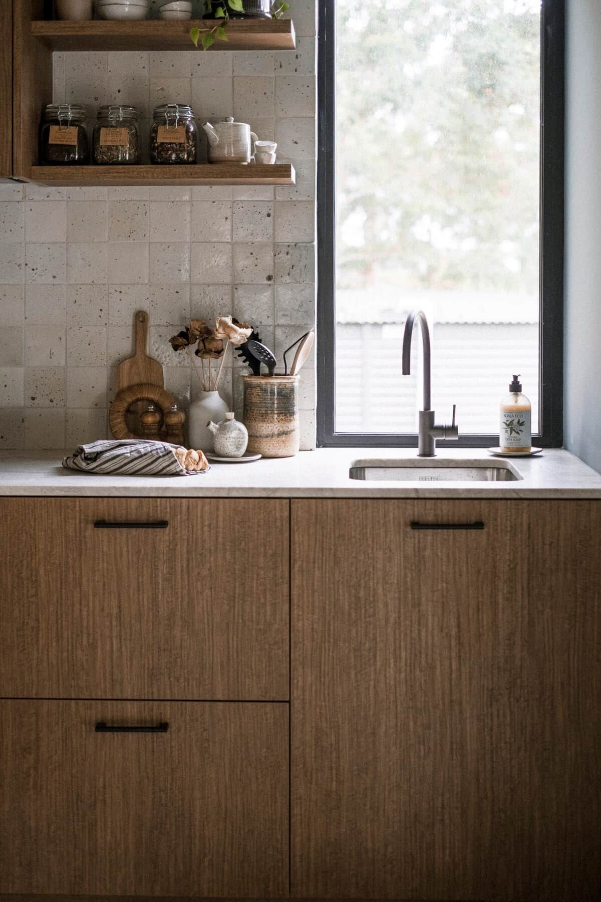A kitchen with wooden cabinets, a window, and various kitchen items on the counter.
