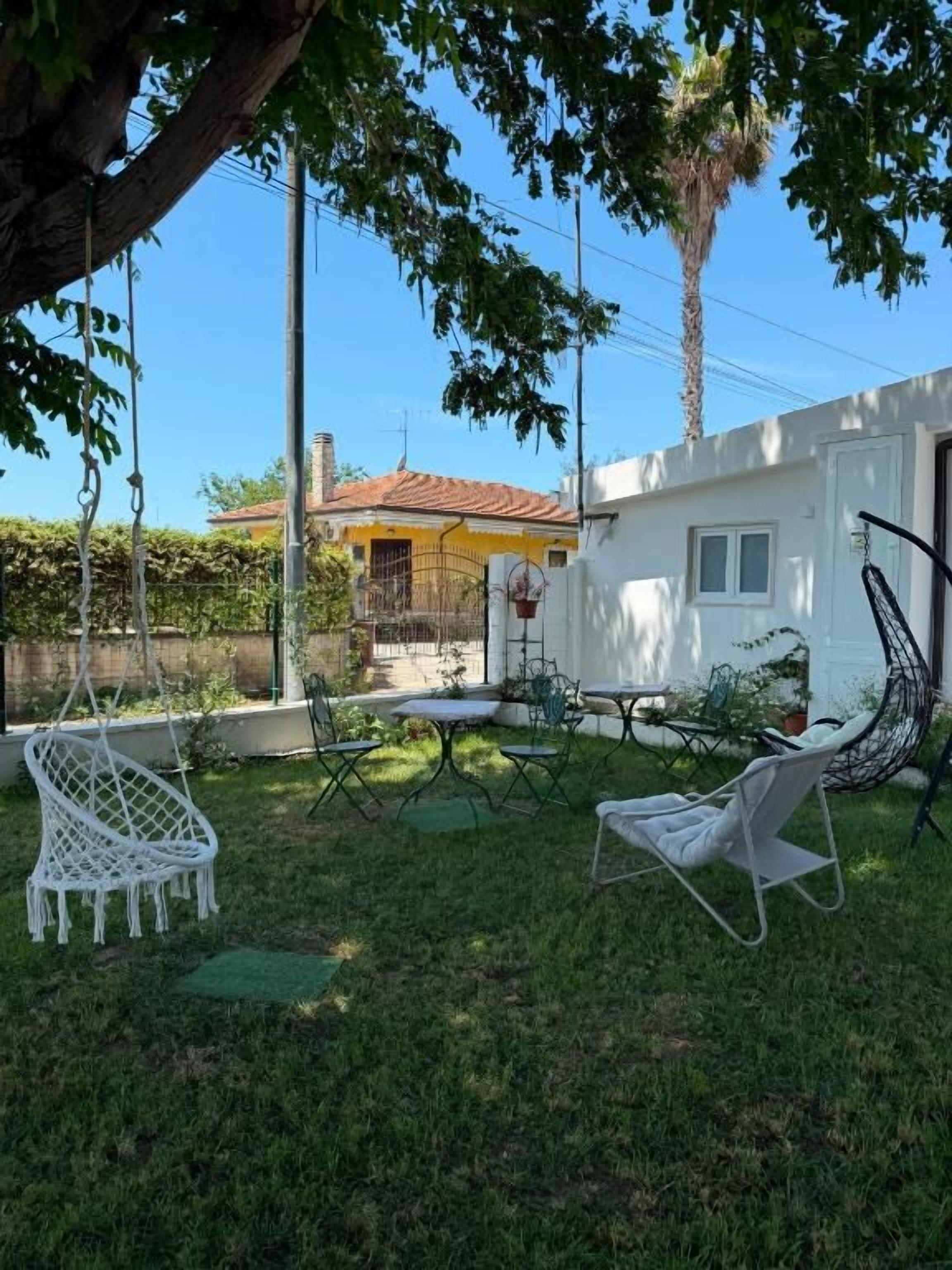 A backyard with a swing set, a dining table, and a chair.