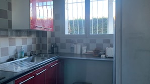 Una cocina con ventana, lavamanos y armarios.