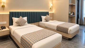 A hotel room with two beds, a bedside table with a phone, an air conditioning unit, and a lamp.