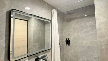 A modern bathroom with a curved sink, a mirror, and a shower enclosure.
