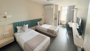 Hotellihuone, jossa on kaksi sänkyä, työpöytä, televisio ja ilmastointilaite.