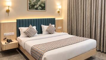 A hotel room with a large bed, two bedside lamps, a wall-mounted artwork, and a curtain.