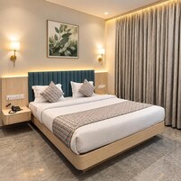 A hotel room with a large bed, two bedside lamps, a wall-mounted artwork, and a curtain.
