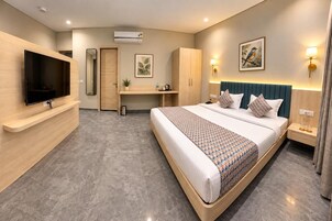 A modern hotel room with a large bed, a desk, a flat-screen TV, and a wardrobe.