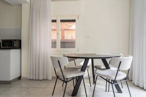 Una cocina moderna con microondas, una mesa de comedor con cuatro sillas y una ventana con persianas.