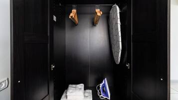 A dark wooden room with a towel, an iron, and two wooden objects hanging on the wall.