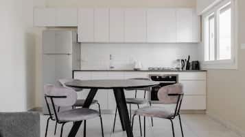 Una cocina moderna con armarios blancos, una mesa redonda y cuatro sillas.