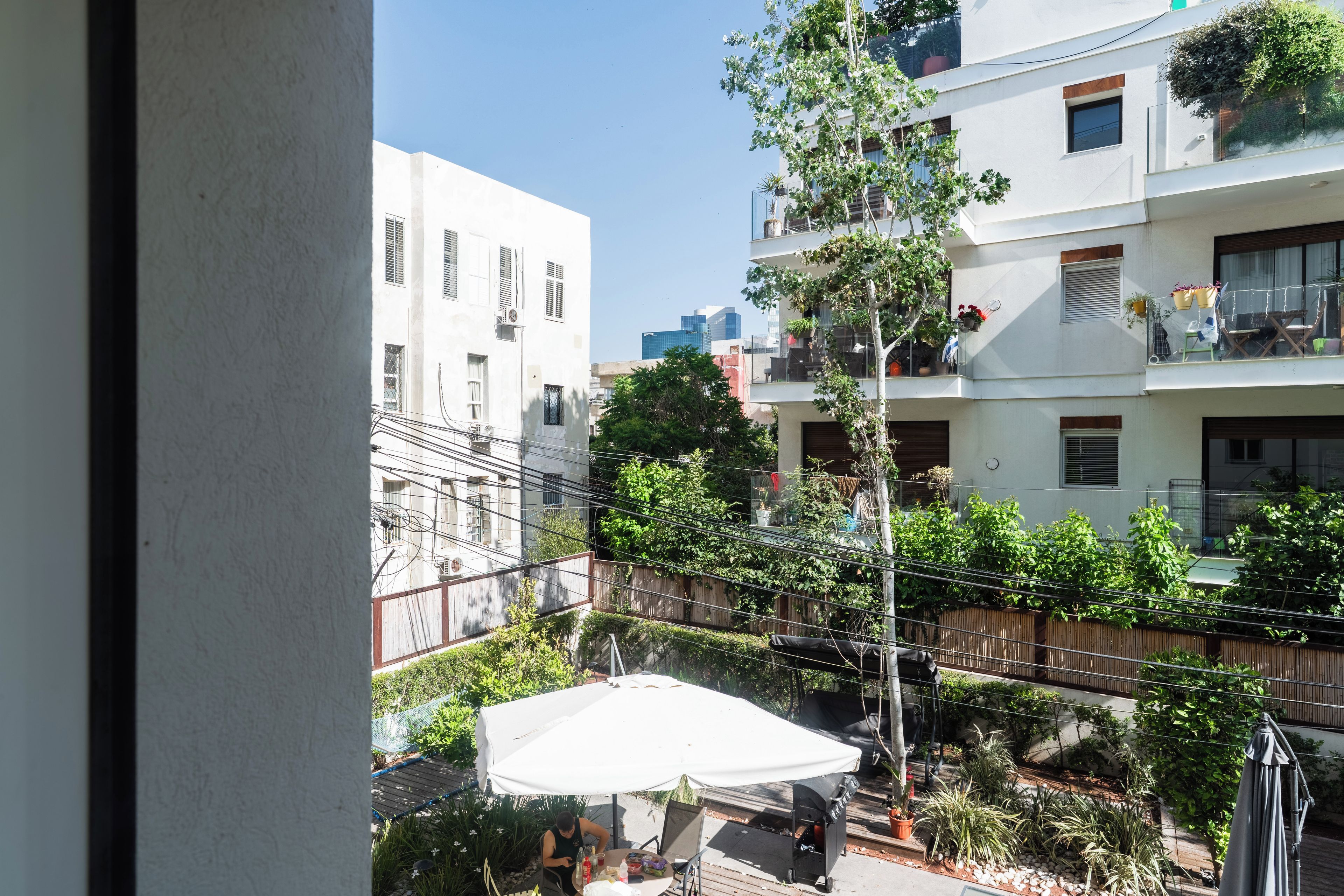 A courtyard with a covered seating area, surrounded by buildings with balconies and potted plants.