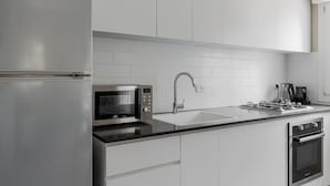 Una cocina moderna con refrigerador de acero inoxidable, microondas integrado, estufa a gas y pileta.