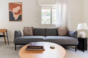 A living room with a grey sofa, a round coffee table, a lamp, and a framed abstract painting on the wall. - Blueground Nahalat Bynamin City view (Tel Aviv-Yafo)