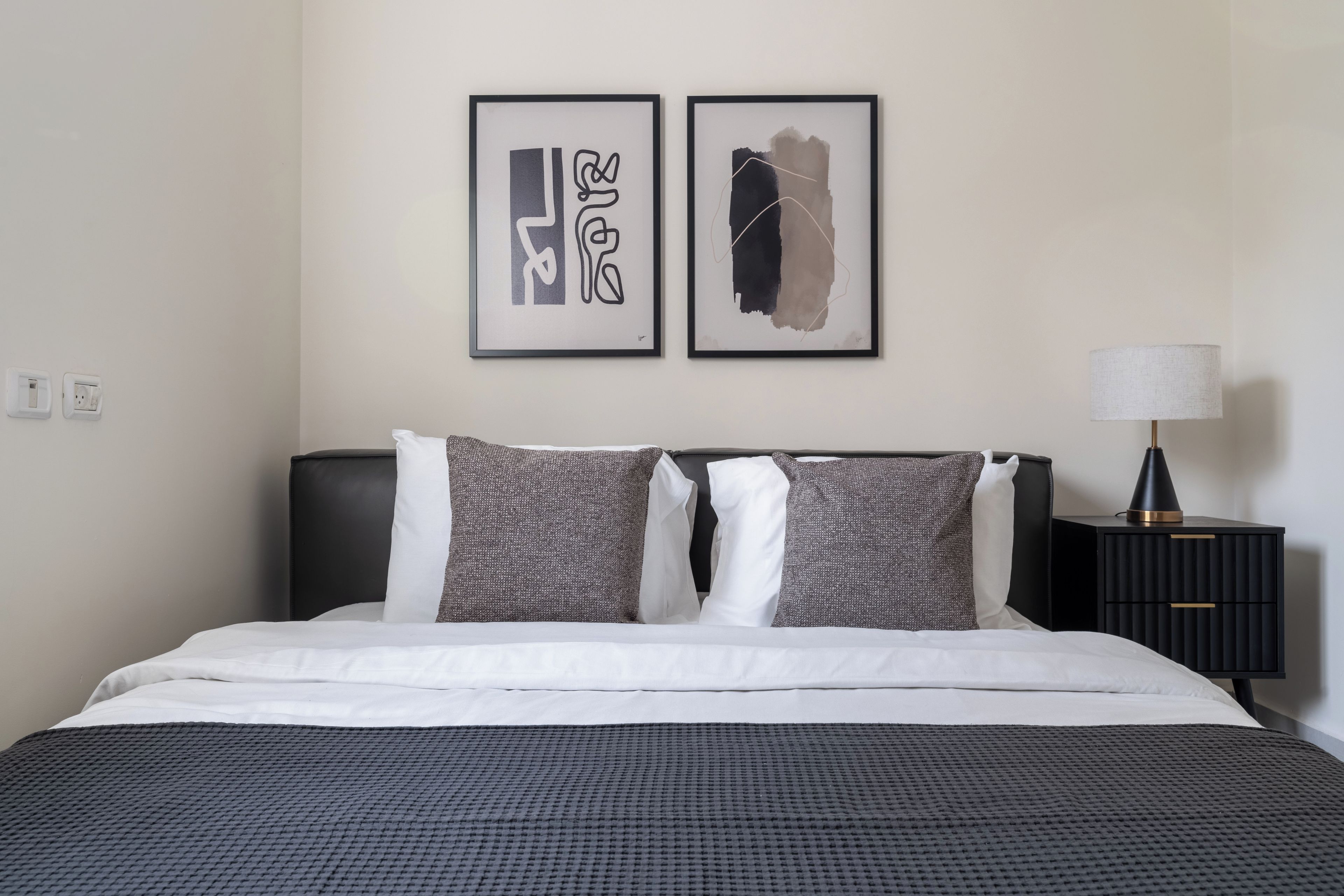 Una cama bien hecha con una colcha estampada, dos almohadas y un cabecero negro.