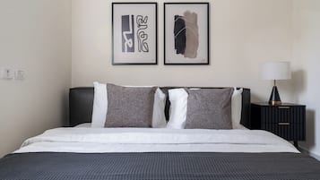 Una cama bien hecha con una colcha estampada, dos almohadas y un cabecero negro.