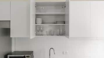 Eine Küche mit einer Mikrowelle, einem Spülbecken und einem Schrank mit Geschirr und Gläsern.