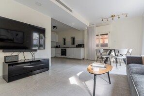 A modern living room with a flat-screen TV, a coffee table, and a sofa. - Blueground Nahalat Bynamin City view (Tel Aviv-Yafo)