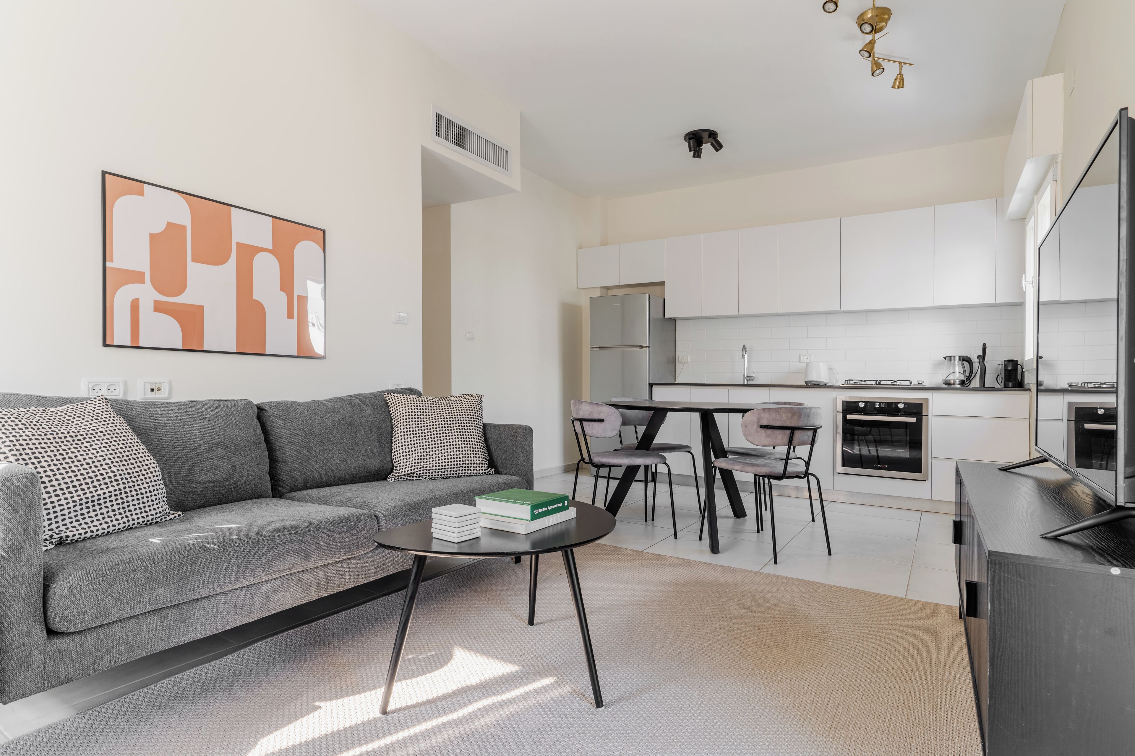 A modern living room with a grey sofa, a coffee table, and a bookshelf.