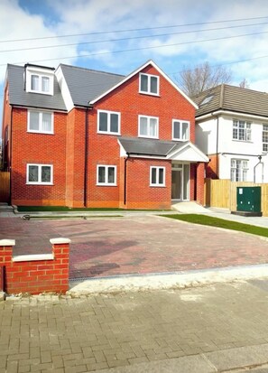 A residential building with a brick facade, multiple windows, and a paved driveway. - Modern 3-Bed Wembley Home, Minutes from Wembley Stadium (Wembley)