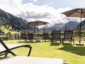 A terrace with outdoor seating, a view of mountains, and a wooden fence. - Holiday Apartment With 1 Bedroom (Rauris)