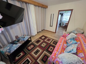 A bedroom with a bed, a TV, a desk, and a mirror.