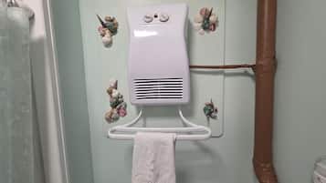 Une salle de bain avec un porte-serviettes sur lequel est posée une serviette ornée du mot «
Relax
», un radiateur blanc fixé au mur et des coquillages décoratifs.